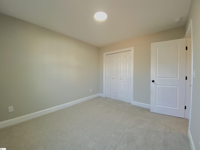 unfurnished bedroom with a closet and light carpet