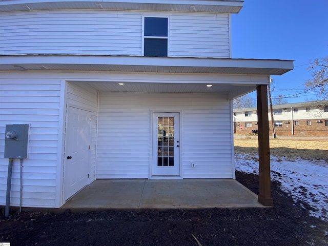 snow covered property entrance with a patio