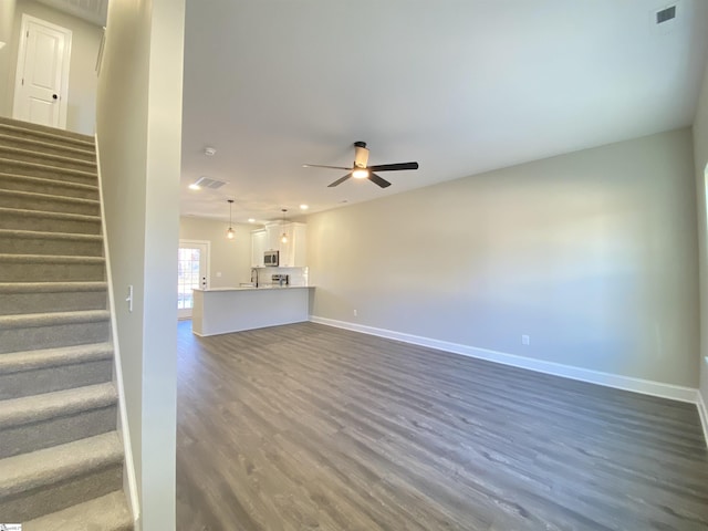 unfurnished living room featuring sink, dark hardwood / wood-style flooring, and ceiling fan