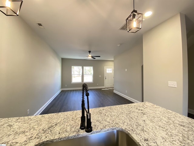 kitchen with sink, light stone counters, ceiling fan, dark hardwood / wood-style floors, and pendant lighting