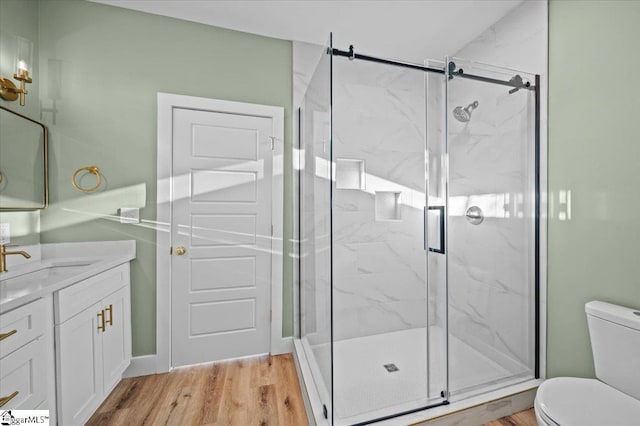 bathroom featuring hardwood / wood-style flooring, toilet, vanity, and a shower with shower door