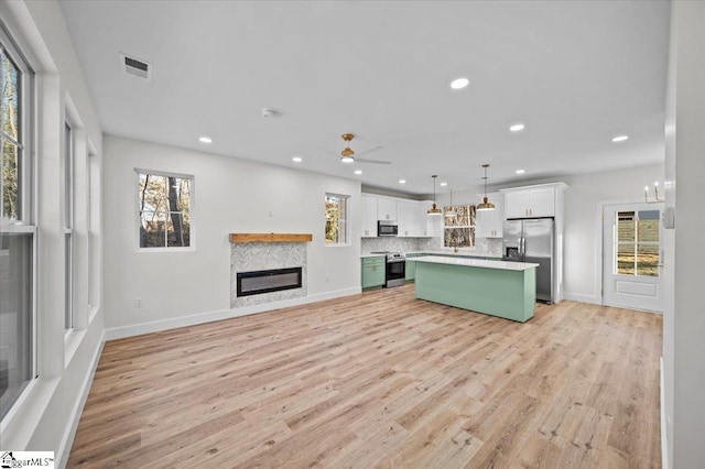 kitchen featuring appliances with stainless steel finishes, ceiling fan, pendant lighting, green cabinetry, and a kitchen island