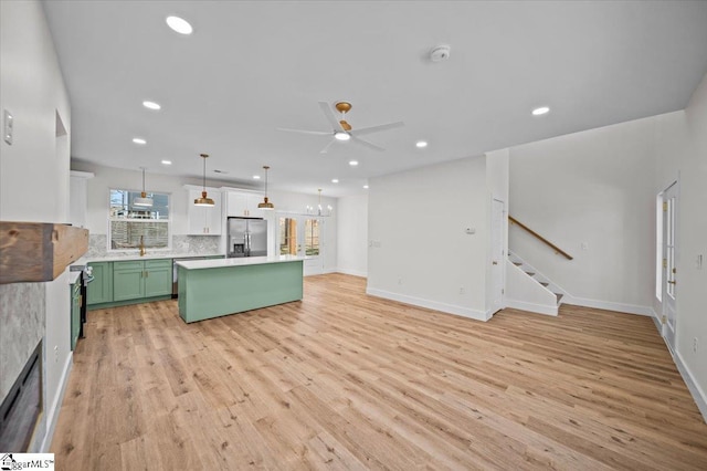 kitchen with green cabinets, a center island, ceiling fan, stainless steel refrigerator with ice dispenser, and pendant lighting