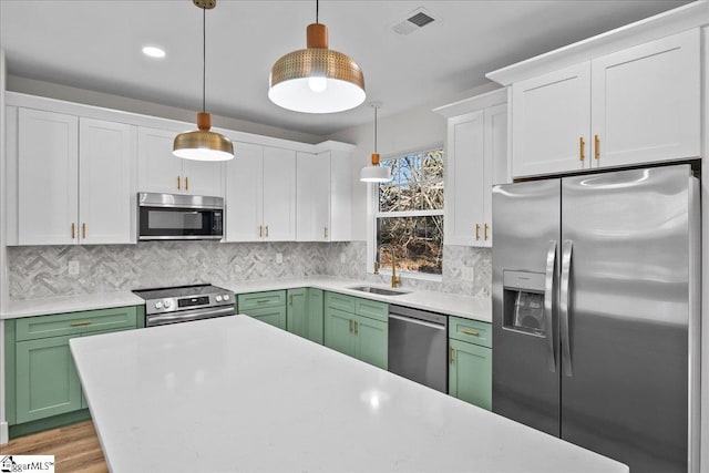 kitchen with stainless steel appliances, pendant lighting, and green cabinets