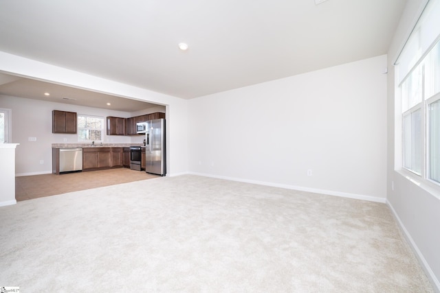 unfurnished living room with sink and light carpet