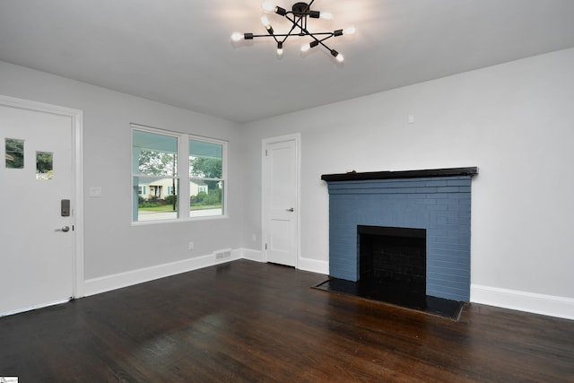 unfurnished living room with a fireplace, a chandelier, and dark hardwood / wood-style flooring