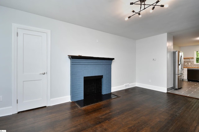 unfurnished living room featuring a notable chandelier, dark wood-type flooring, and a fireplace