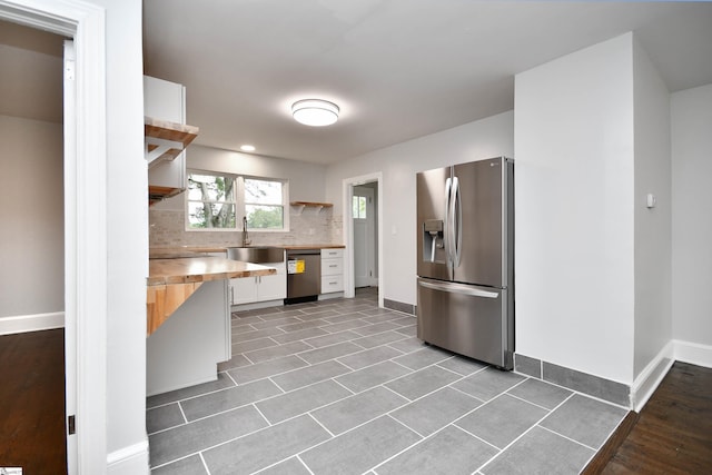 kitchen featuring sink, white cabinets, tasteful backsplash, wood counters, and appliances with stainless steel finishes