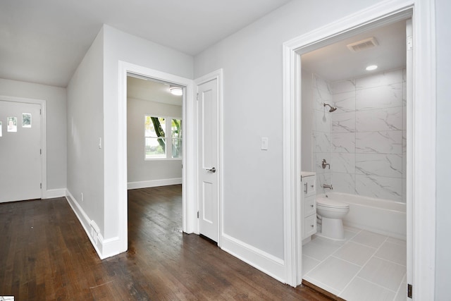 interior space featuring toilet, hardwood / wood-style floors, and tiled shower / bath combo