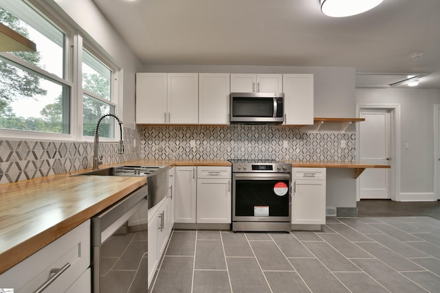 kitchen with butcher block counters, white cabinets, sink, and appliances with stainless steel finishes