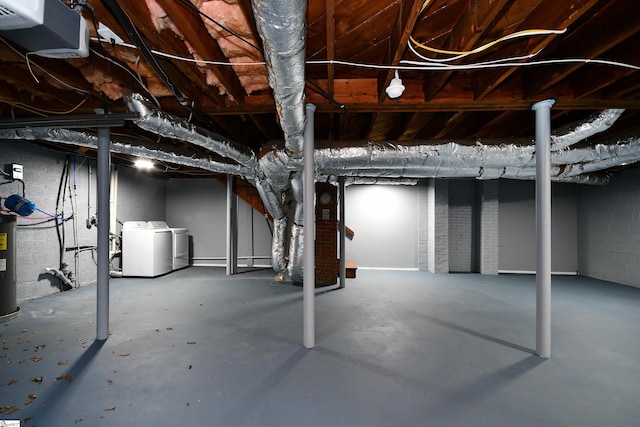 basement featuring electric water heater, washer and clothes dryer, and heating unit