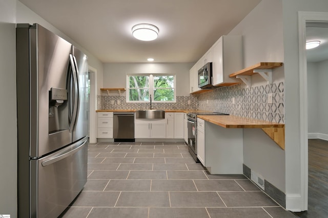 kitchen with tile patterned floors, wood counters, white cabinetry, appliances with stainless steel finishes, and sink