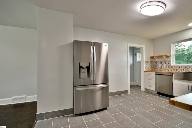 kitchen featuring stainless steel appliances, butcher block countertops, decorative backsplash, white cabinets, and sink