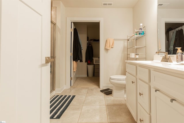 bathroom featuring toilet, tile patterned flooring, a shower with shower door, and vanity