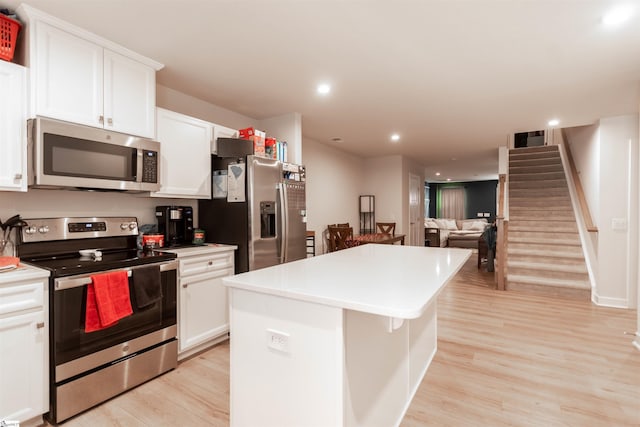 kitchen with stainless steel appliances, white cabinetry, light hardwood / wood-style floors, and a center island