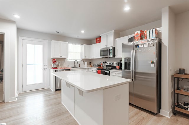 kitchen with sink, a kitchen island, white cabinets, and appliances with stainless steel finishes