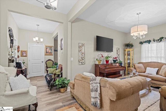 living room with beam ceiling, light wood-type flooring, and an inviting chandelier