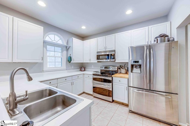 kitchen featuring stainless steel appliances, light tile patterned flooring, white cabinets, and sink