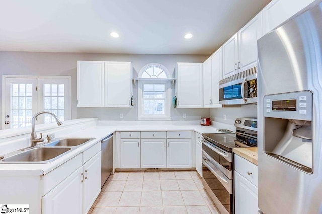 kitchen with appliances with stainless steel finishes, white cabinets, sink, and light tile patterned floors