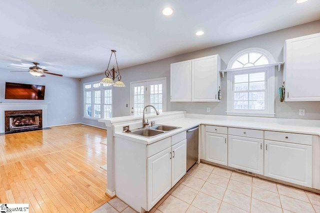 kitchen featuring stainless steel dishwasher, white cabinets, sink, and hanging light fixtures