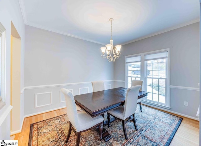 dining area featuring an inviting chandelier, ornamental molding, and light hardwood / wood-style flooring