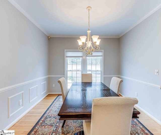 dining area with a notable chandelier, ornamental molding, and light hardwood / wood-style floors