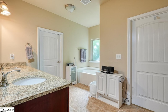 bathroom with tile patterned floors, a tub, and vanity