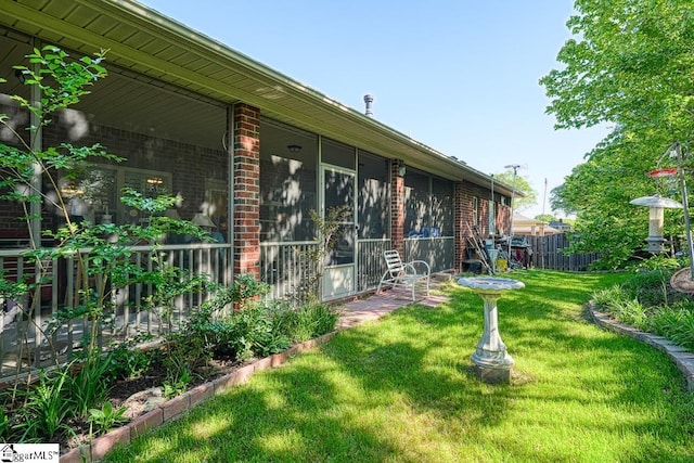 view of home's exterior with a sunroom and a lawn