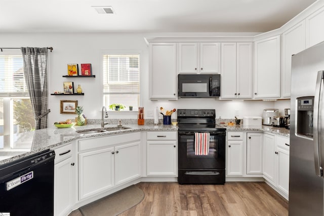 kitchen featuring sink, light hardwood / wood-style floors, white cabinets, and black appliances