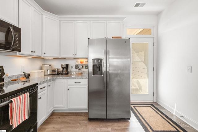 kitchen featuring black appliances, light wood-type flooring, white cabinets, and light stone counters