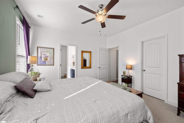 bedroom with ceiling fan, ensuite bath, and light carpet