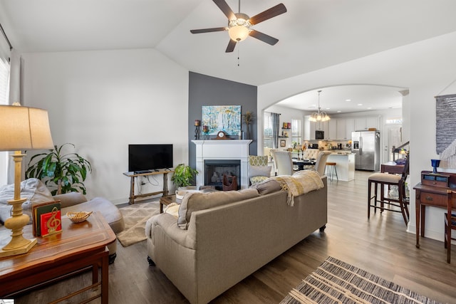 living room featuring ceiling fan with notable chandelier, lofted ceiling, and light wood-type flooring