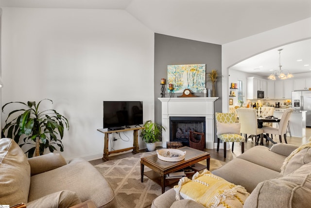 living room with an inviting chandelier, vaulted ceiling, and light hardwood / wood-style flooring