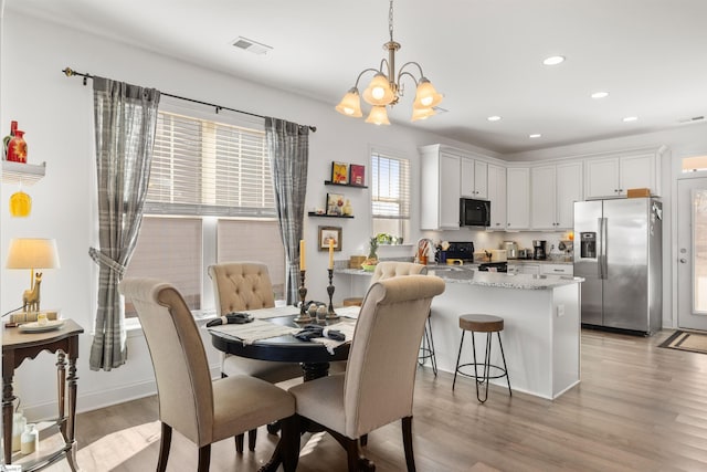 kitchen featuring range with electric cooktop, white cabinets, decorative light fixtures, light stone countertops, and stainless steel refrigerator with ice dispenser