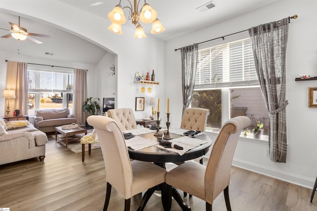 dining area with ceiling fan with notable chandelier, hardwood / wood-style flooring, and a healthy amount of sunlight