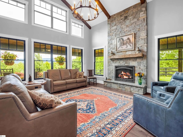 living room with an inviting chandelier, beamed ceiling, wood-type flooring, high vaulted ceiling, and a stone fireplace