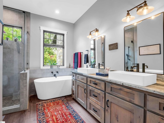 bathroom with hardwood / wood-style flooring, shower with separate bathtub, and vanity