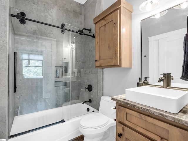 full bathroom featuring toilet, combined bath / shower with glass door, and vanity