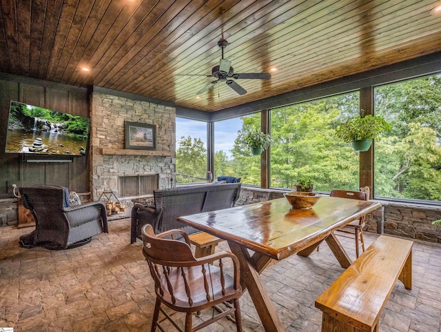 sunroom featuring ceiling fan, wood ceiling, a wealth of natural light, and a fireplace