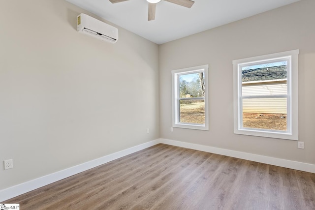 unfurnished room featuring light wood-type flooring, a wall unit AC, and ceiling fan