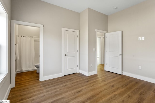 unfurnished bedroom featuring hardwood / wood-style floors, a closet, and connected bathroom