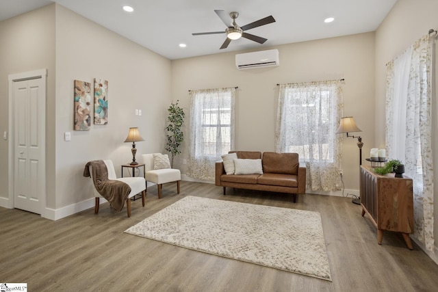 living area featuring wood-type flooring, ceiling fan, and an AC wall unit