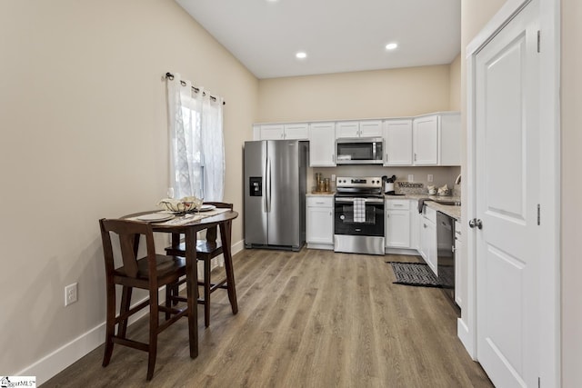 kitchen featuring appliances with stainless steel finishes, white cabinetry, light wood-type flooring, and sink