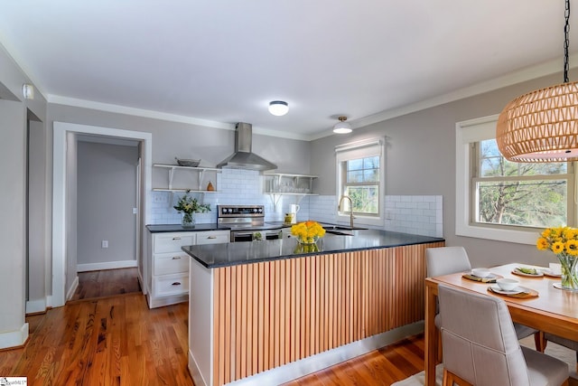 kitchen featuring light hardwood / wood-style floors, stainless steel range with electric stovetop, wall chimney exhaust hood, white cabinets, and sink