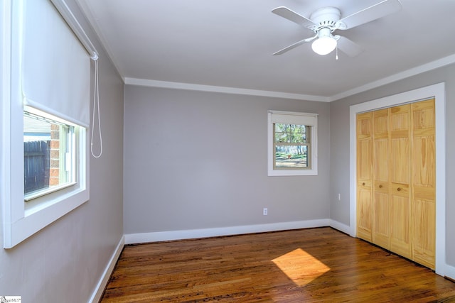 unfurnished bedroom with a closet, ornamental molding, ceiling fan, and dark hardwood / wood-style flooring