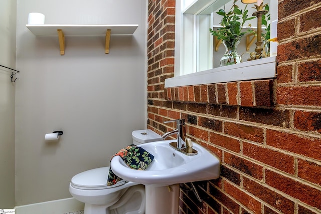 bathroom with toilet and brick wall