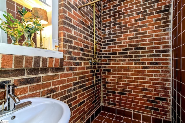 bathroom featuring sink and brick wall