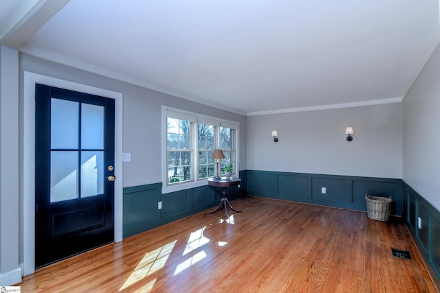 entryway with light hardwood / wood-style flooring and crown molding