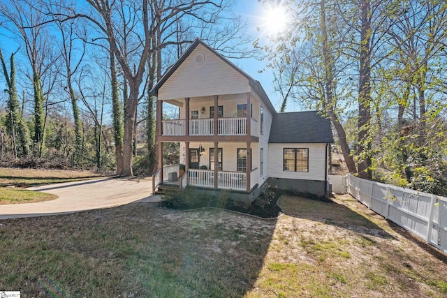 back of house with a balcony, a porch, and a lawn