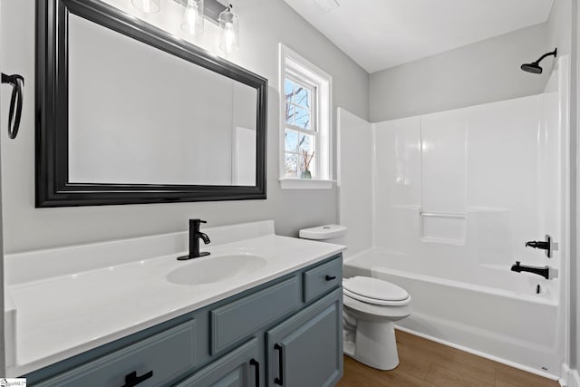 full bathroom featuring toilet, washtub / shower combination, wood-type flooring, and vanity